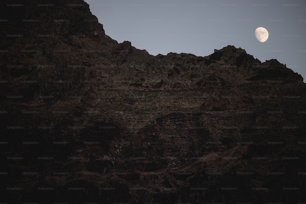 La lune se couche sur une montagne rocheuse