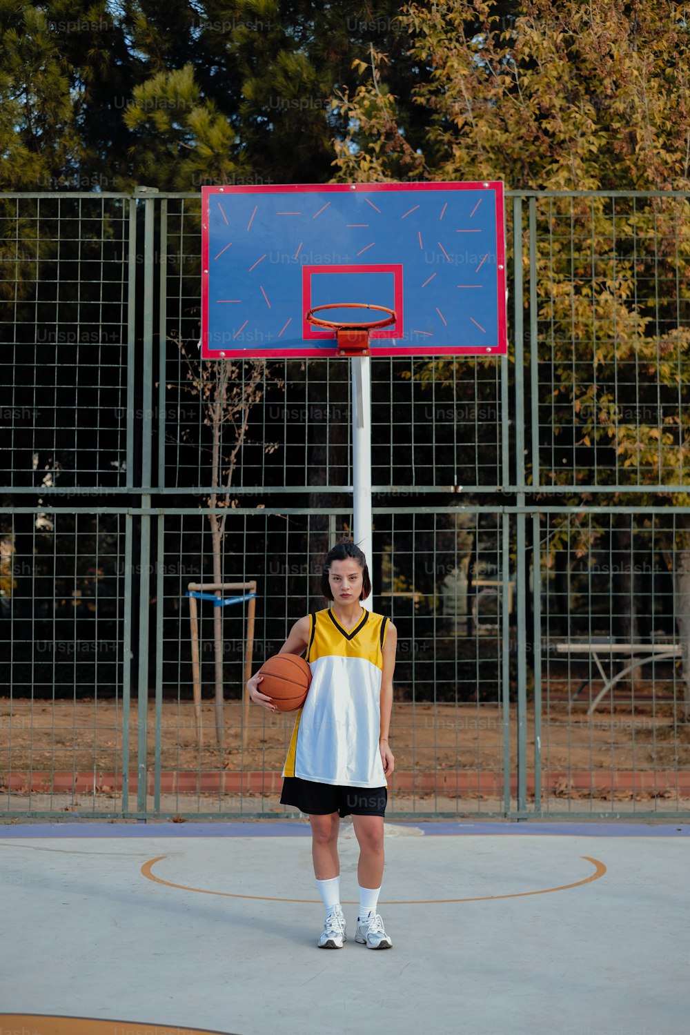 a young woman holding a basketball on a basketball court