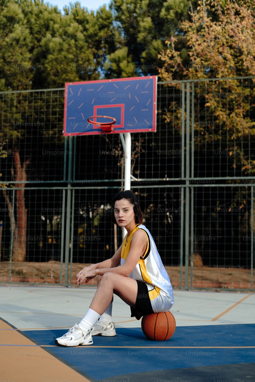 a woman sitting on a basketball court with a basketball