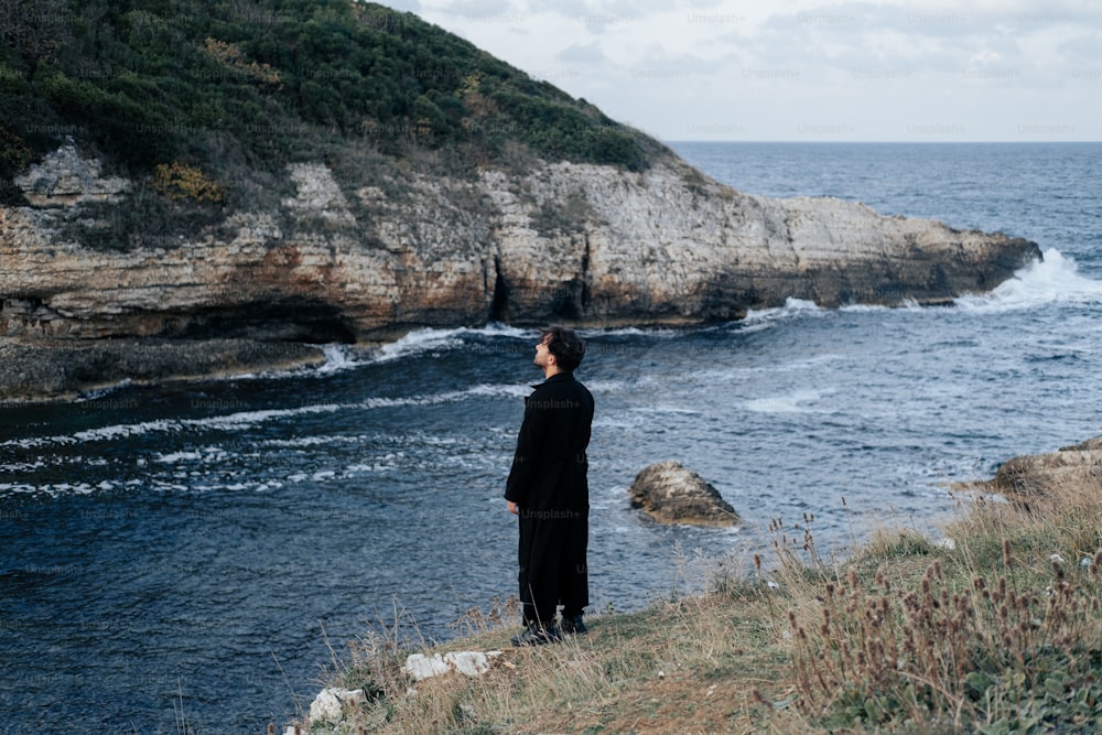 um homem em pé em um penhasco com vista para o oceano