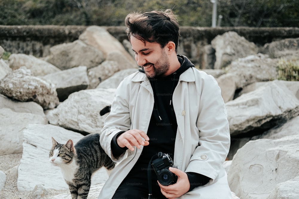 um homem segurando uma câmera e acariciando um gato