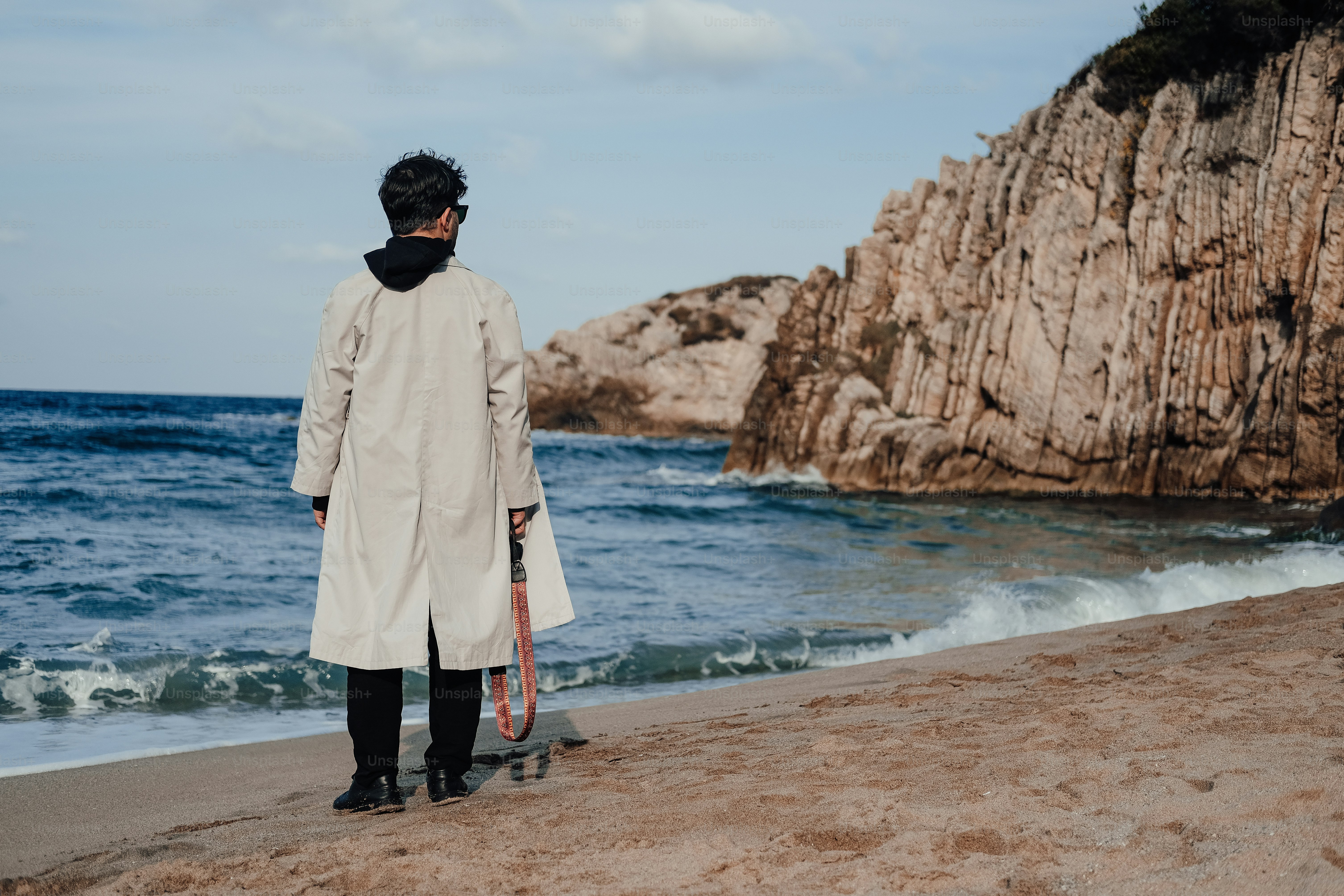 a man standing on a beach holding a tennis racquet