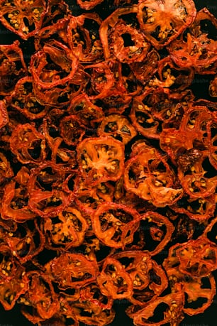 a pile of dried red peppers on a black surface