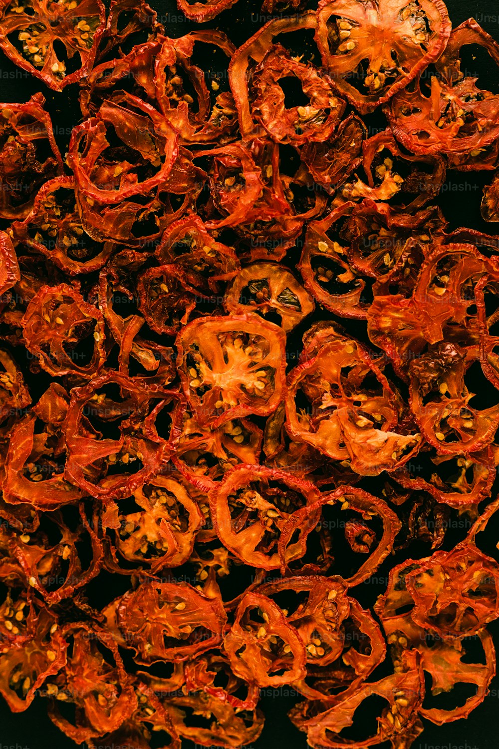 a pile of dried red peppers on a black surface