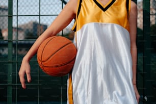 a girl in a yellow and white dress holding a basketball
