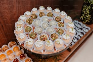 Una mesa cubierta con muchos cupcakes cubiertos de glaseado