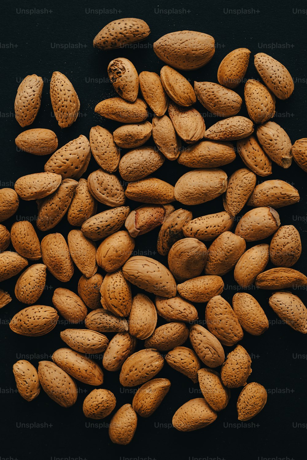 a pile of peanuts on a black surface