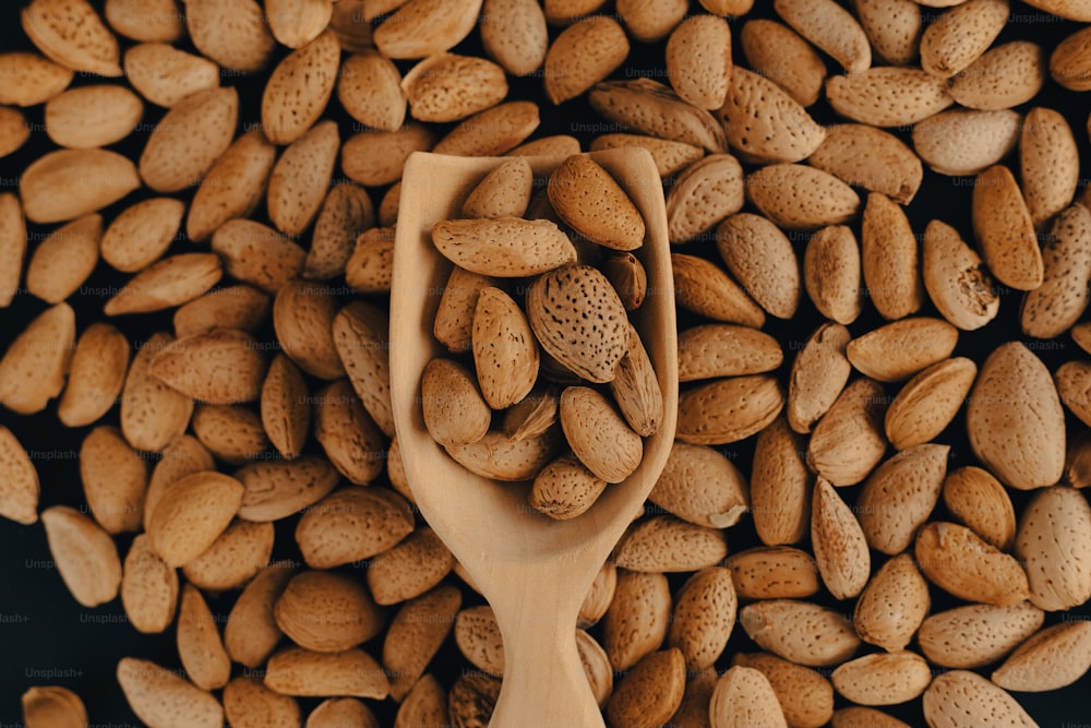 une cuillère en bois remplie de cacahuètes sur le dessus d’une table