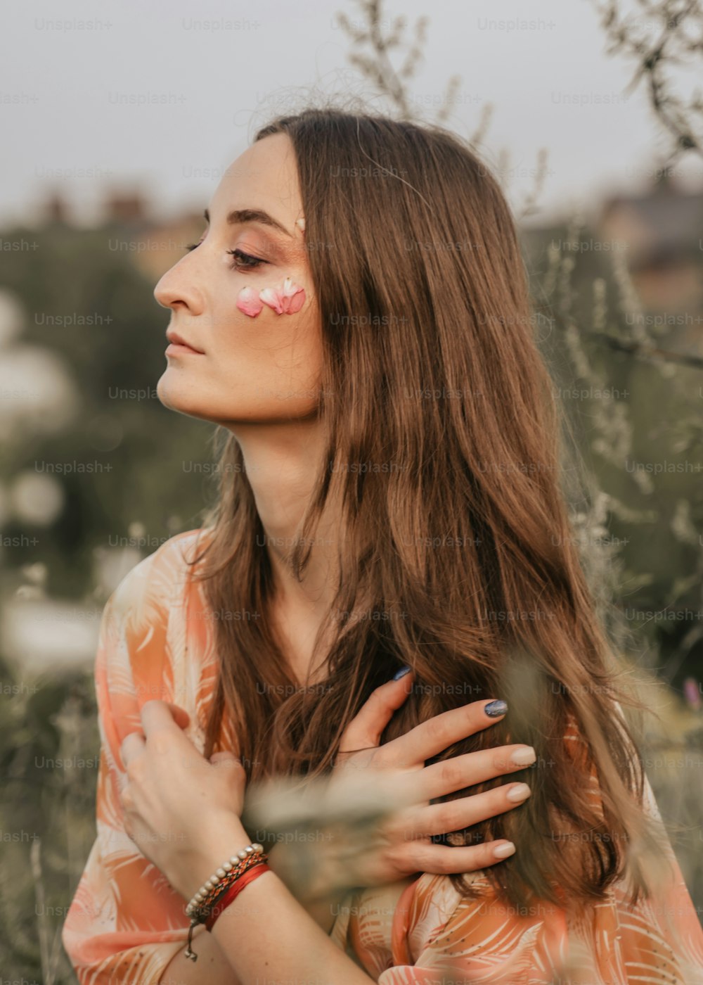 a woman standing in a field with her hands on her chest