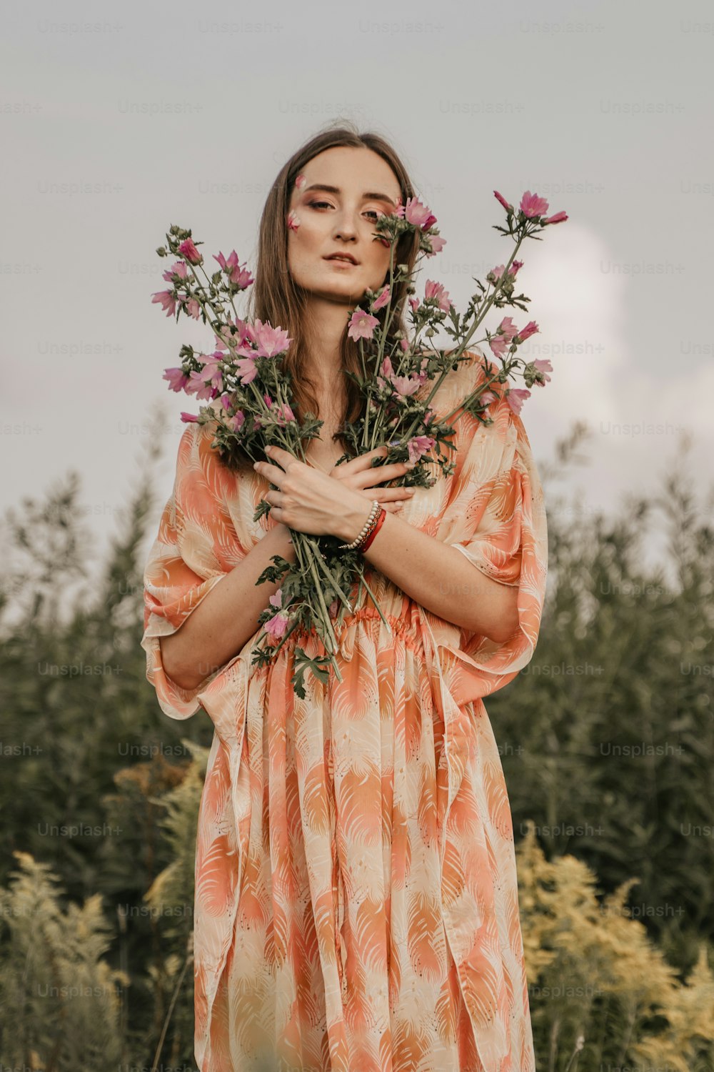 a woman in an orange dress holding a bunch of flowers