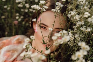 uma mulher escondida atrás de um ramo de flores