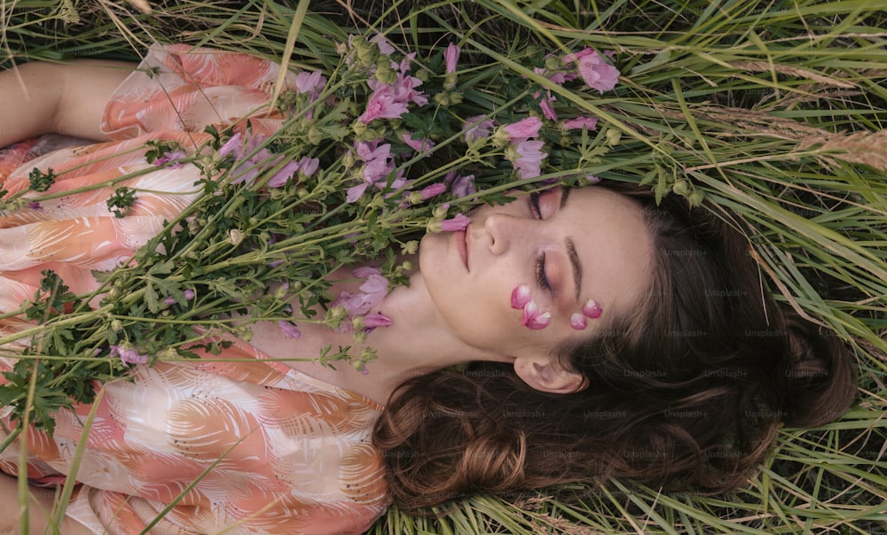草の中に横たわり、花を咲かせる女性