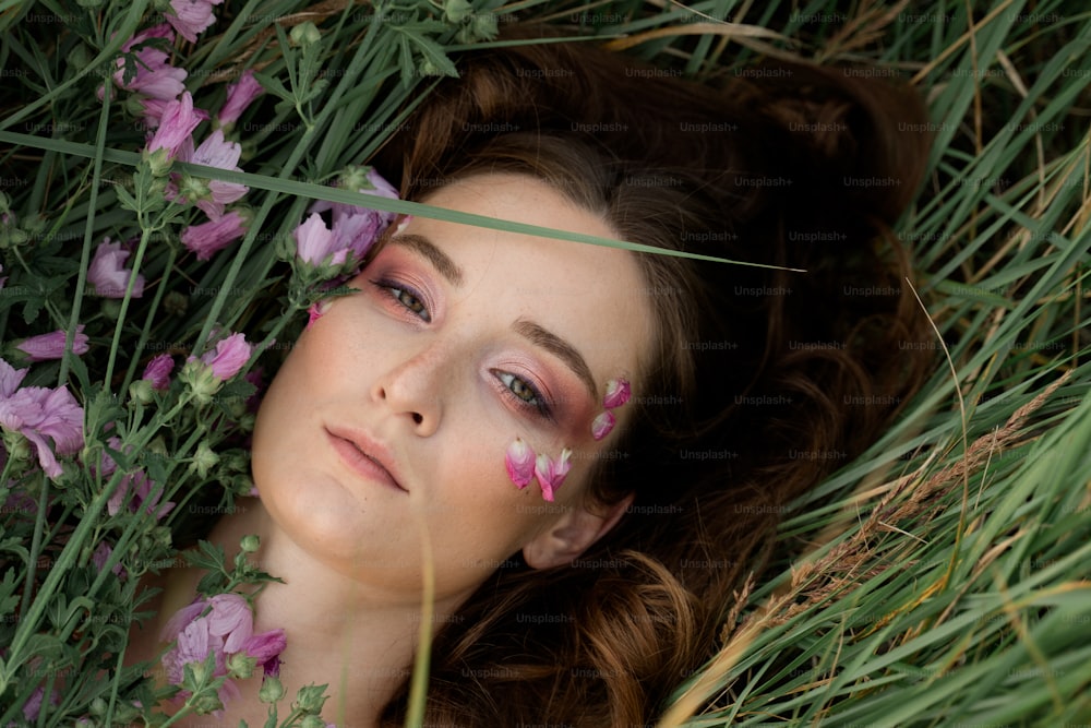 a woman laying in the grass with flowers on her face