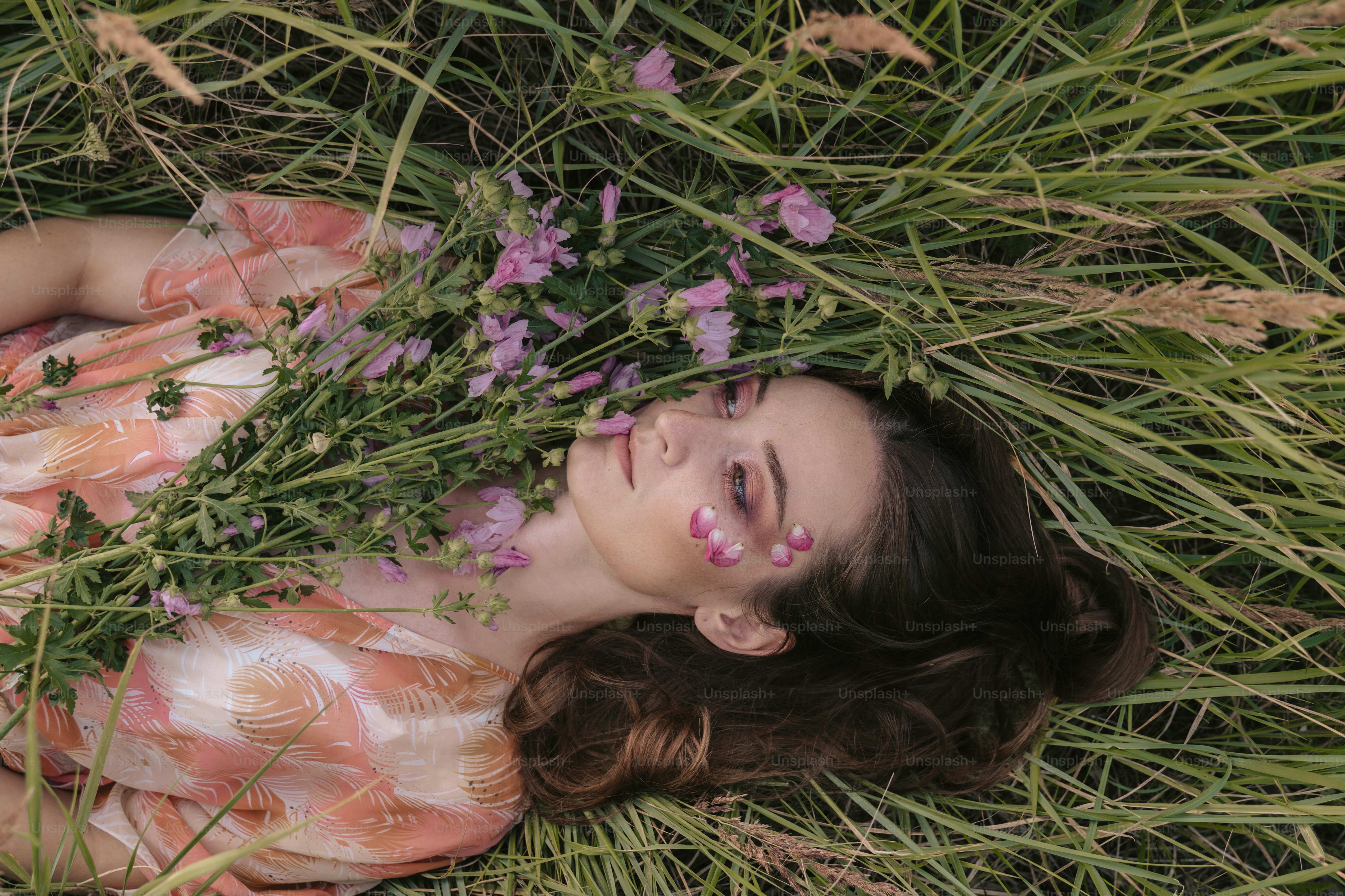 a woman laying in the grass with flowers in her hair