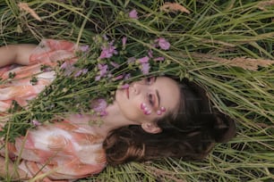 a woman laying in the grass with flowers in her hair