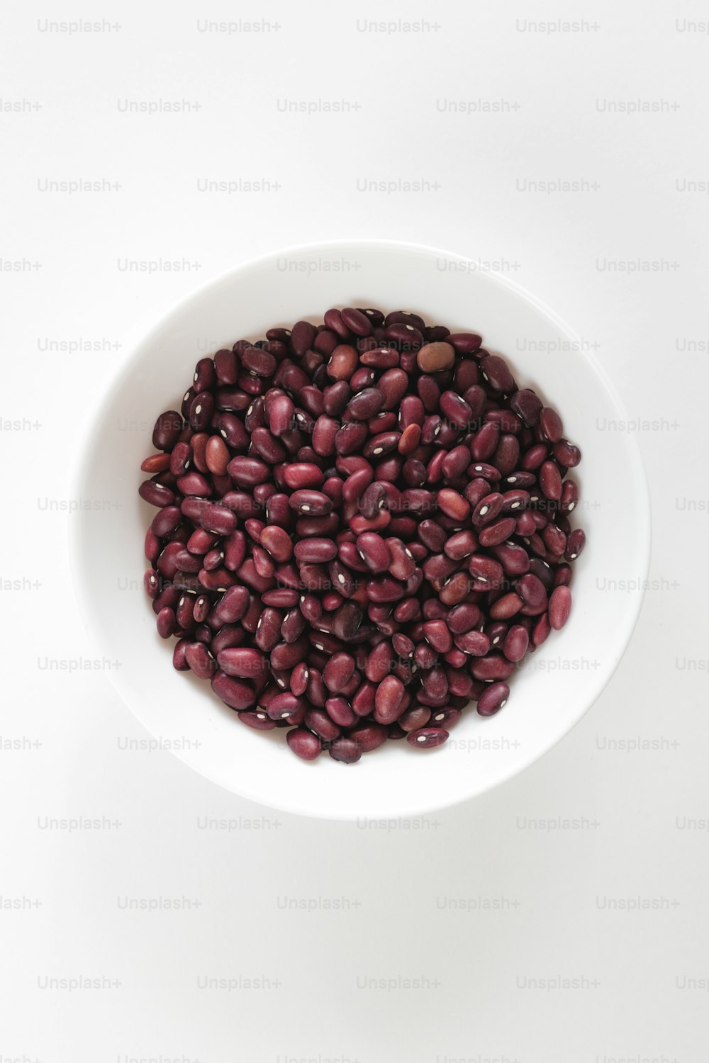 a white bowl filled with red beans on top of a white table