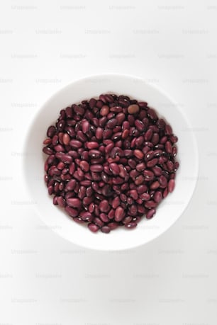 a white bowl filled with red beans on top of a white table