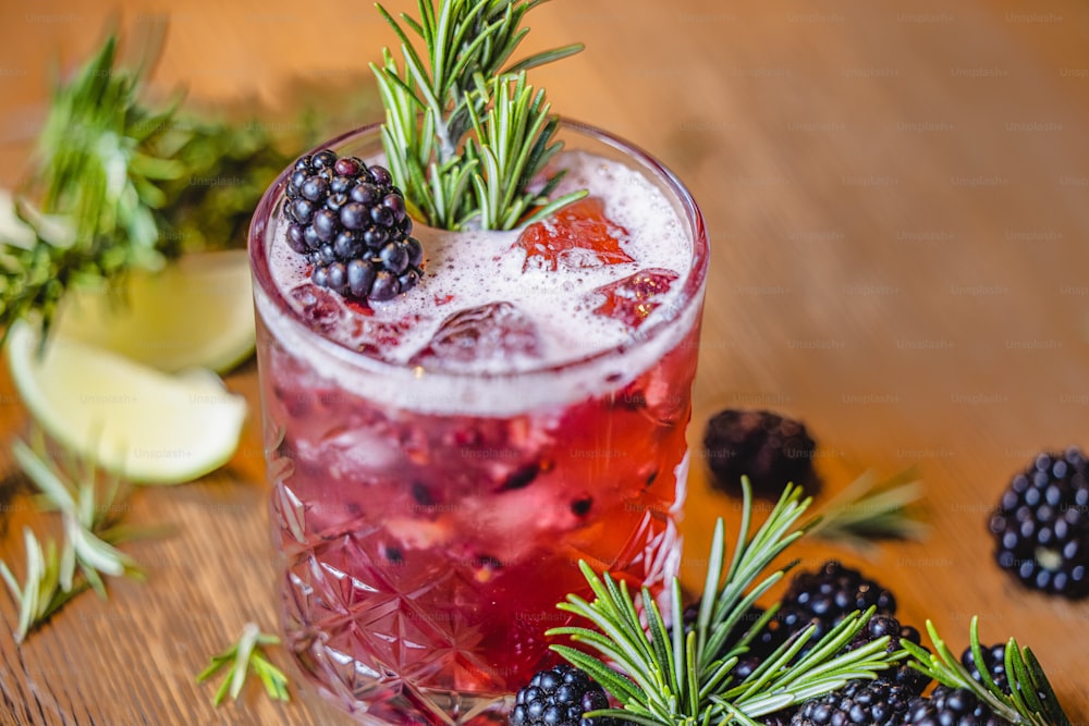 a glass filled with a drink and garnished with blackberries