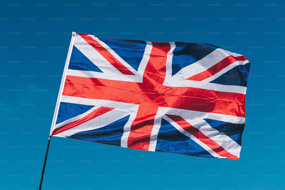 a british flag flying in the blue sky