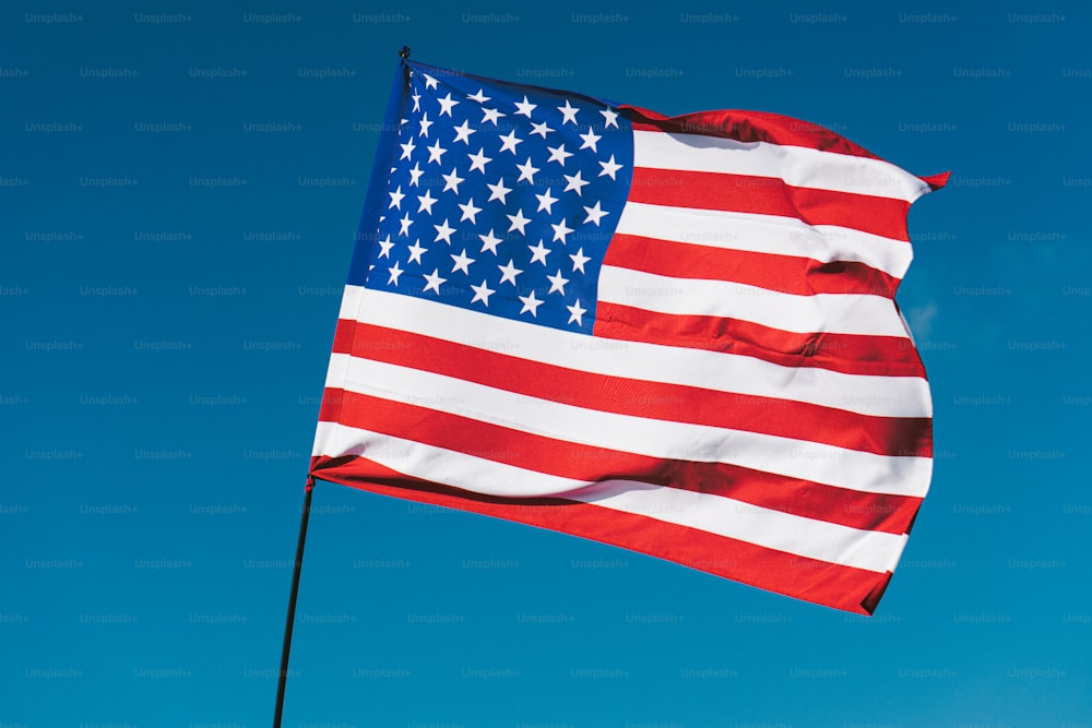 a large american flag flying in the blue sky