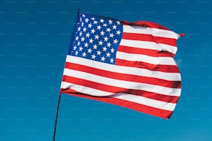 a large american flag flying in the blue sky