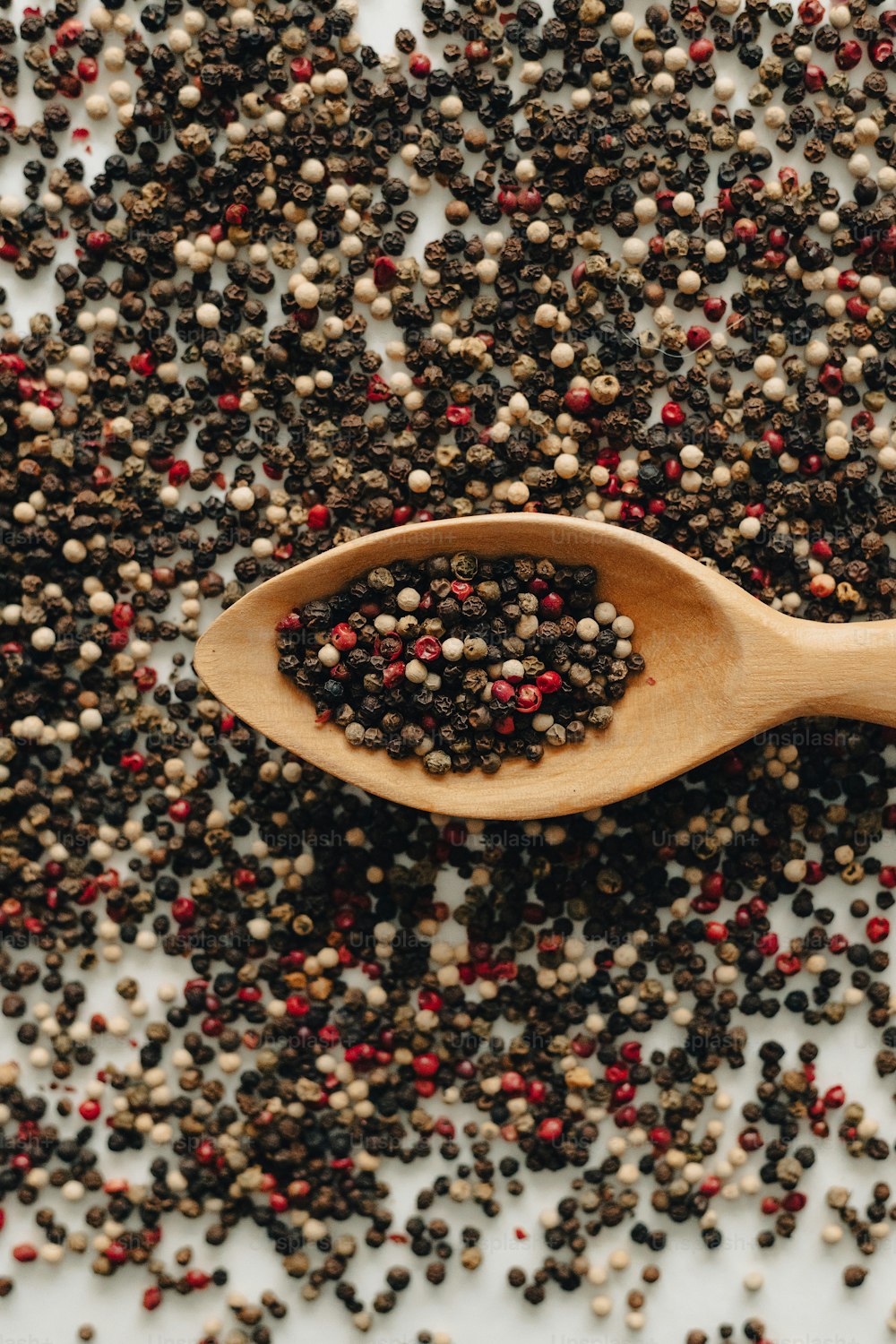 a wooden spoon filled with black and red seeds