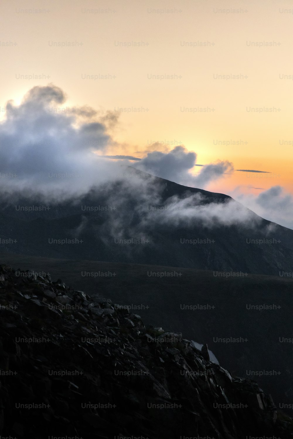 uma montanha coberta de nuvens ao pôr do sol