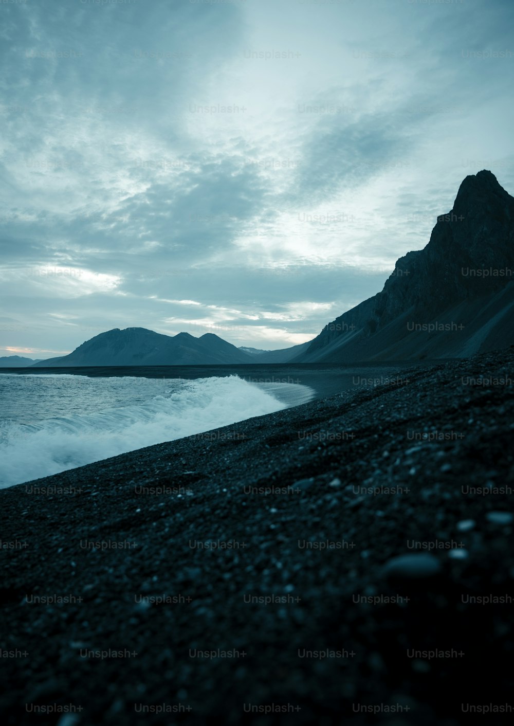 a black beach with a mountain in the background