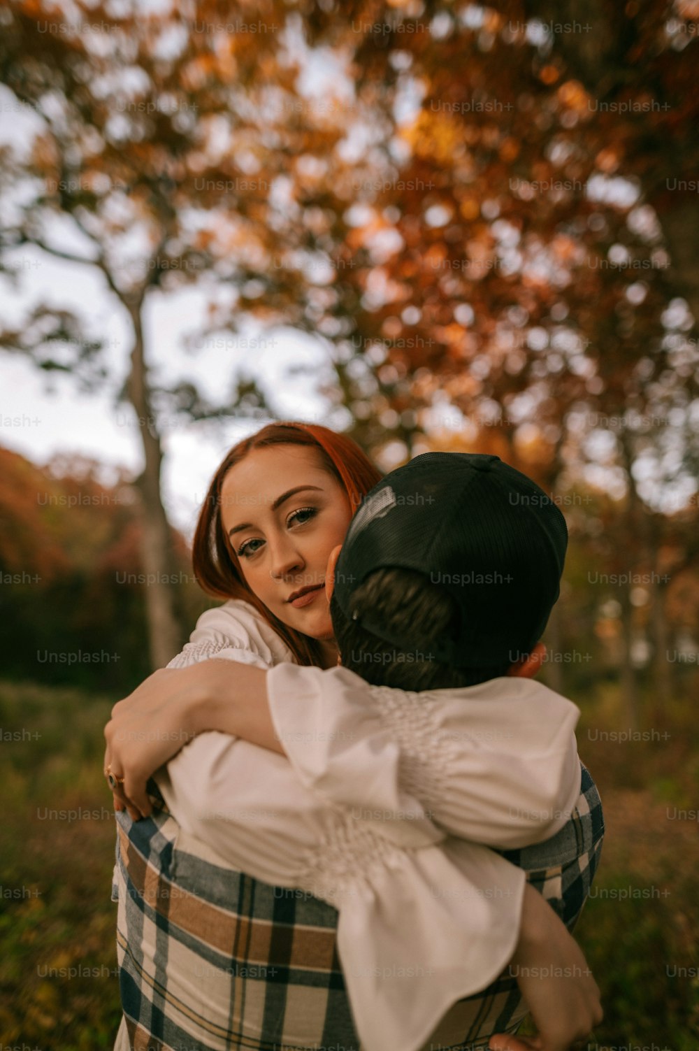 a woman is hugging a man in the woods