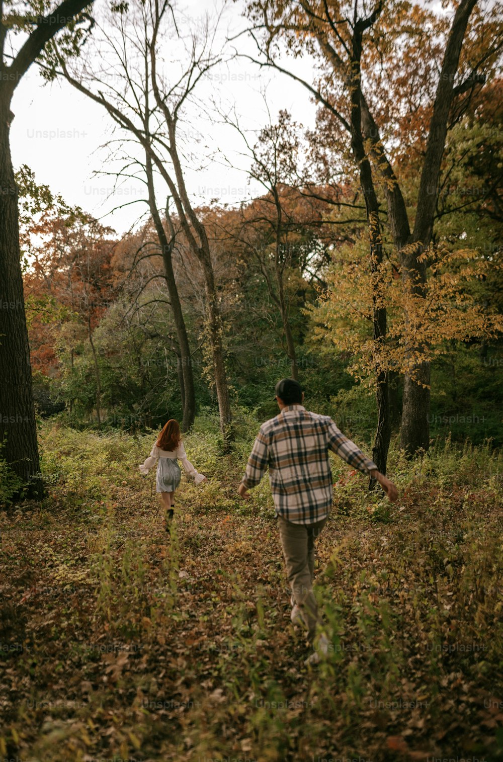 a man and a woman walking through a forest