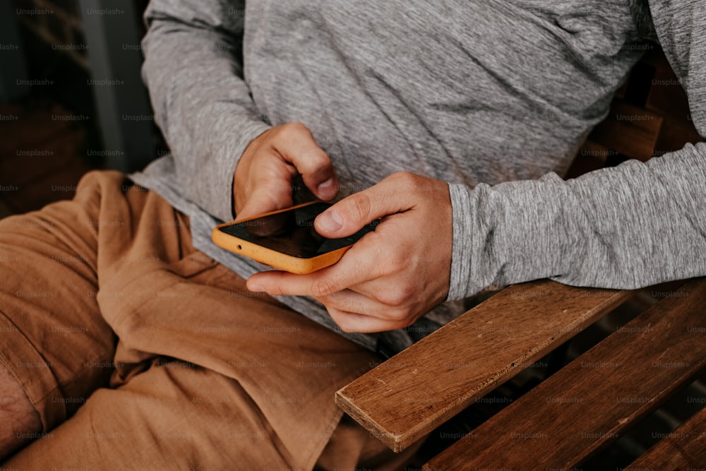 携帯電話��を使ってベンチに座っている男性