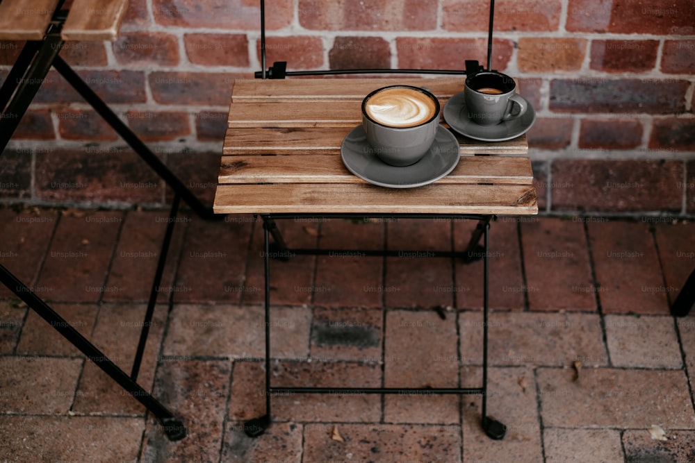 a wooden table topped with two cups of coffee