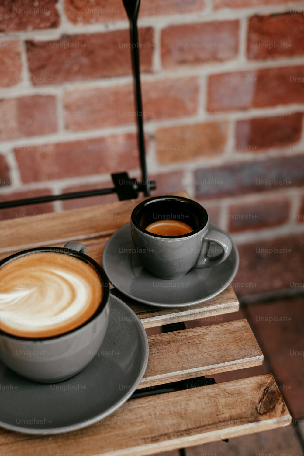 duas xícaras de café sentadas em cima de uma mesa de madeira