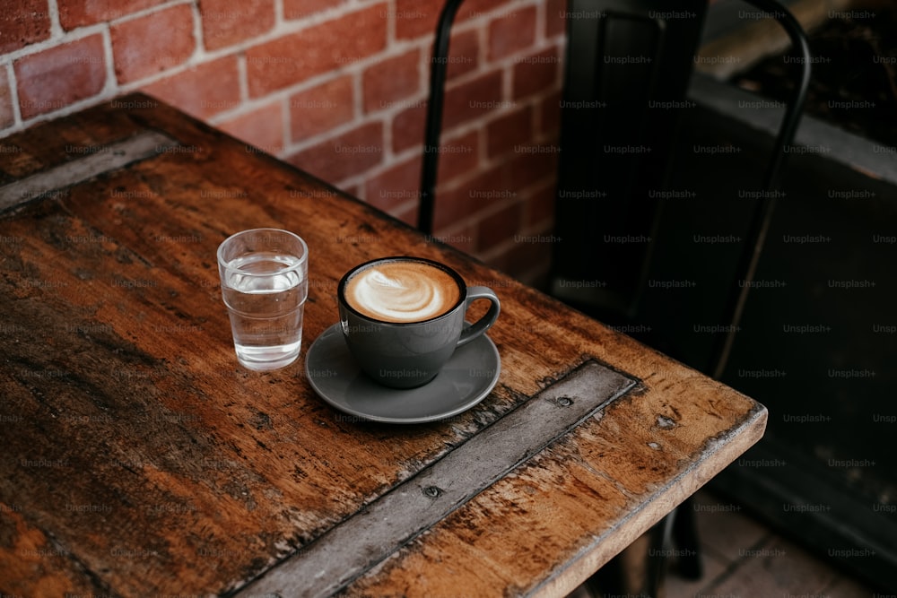 uma xícara de café e um copo de água sobre uma mesa