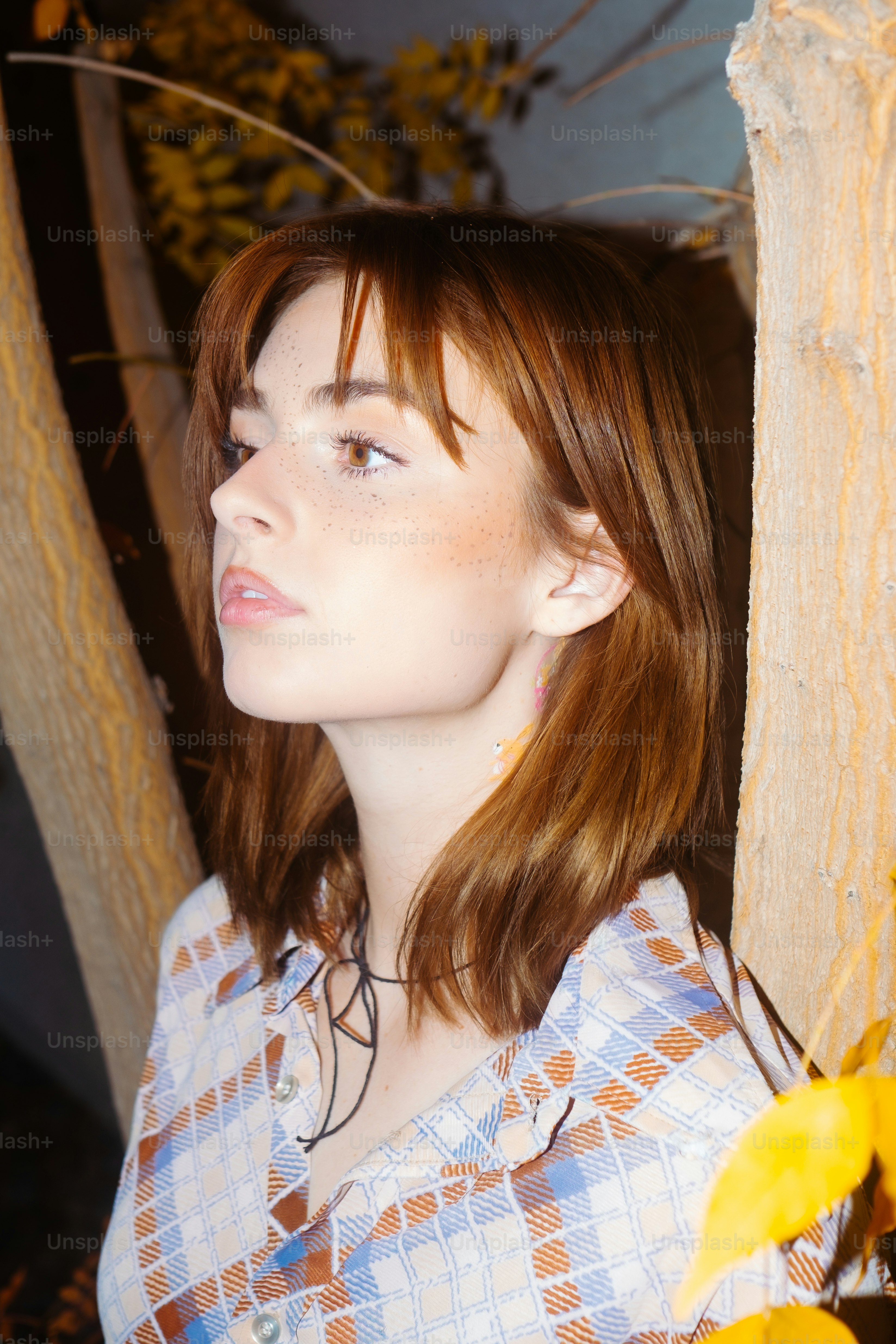 Una mujer pelirroja de pie junto a un árbol