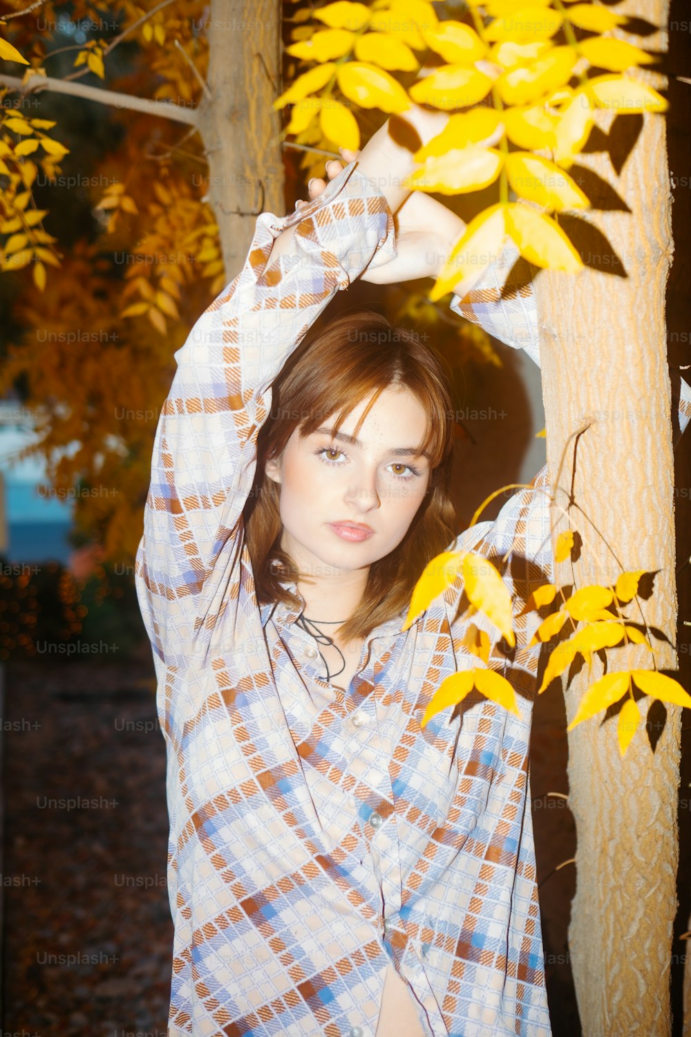 Eine Frau, die neben einem Baum mit gelben Blättern steht