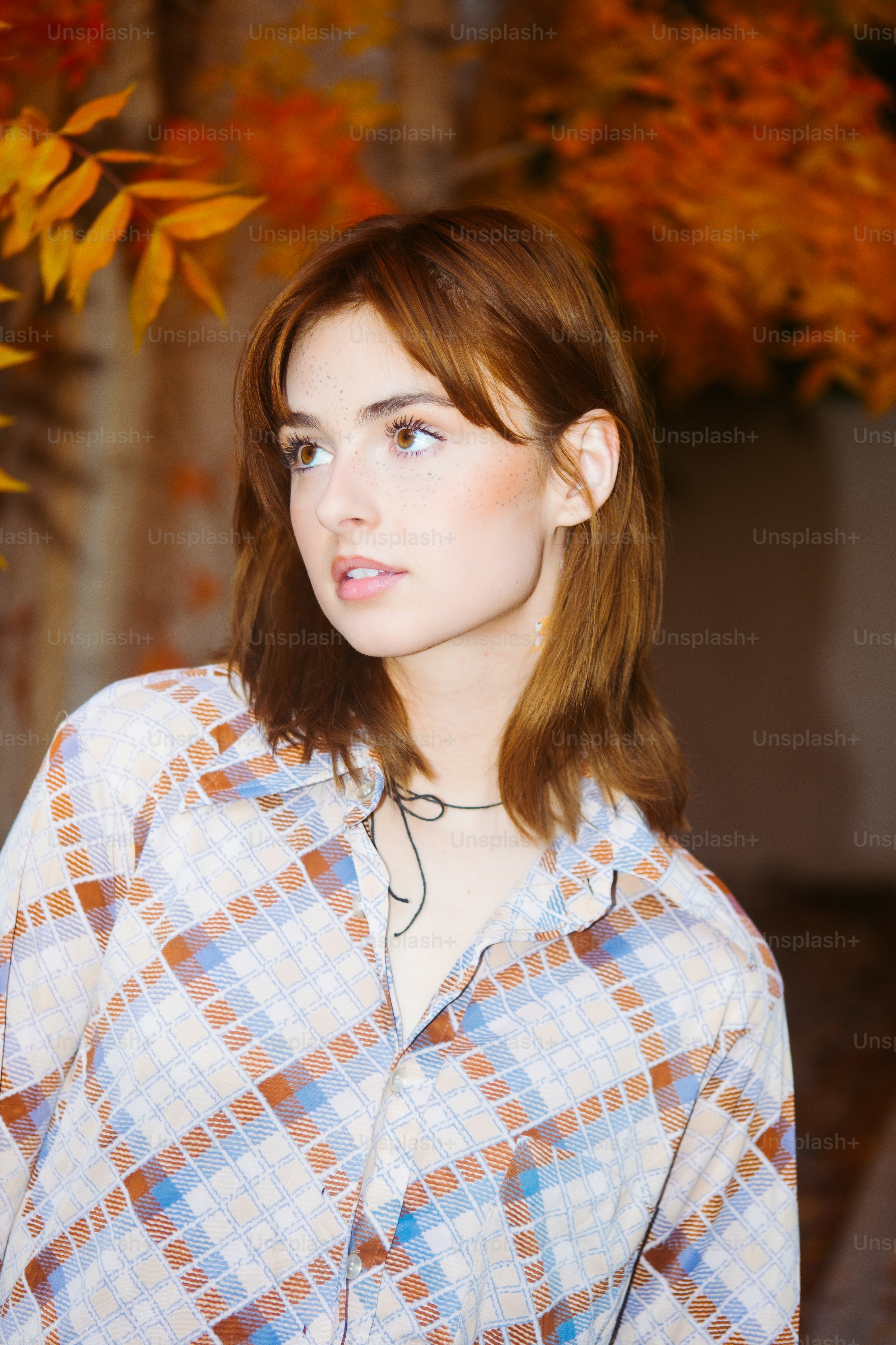 a woman standing in front of a tree with orange leaves