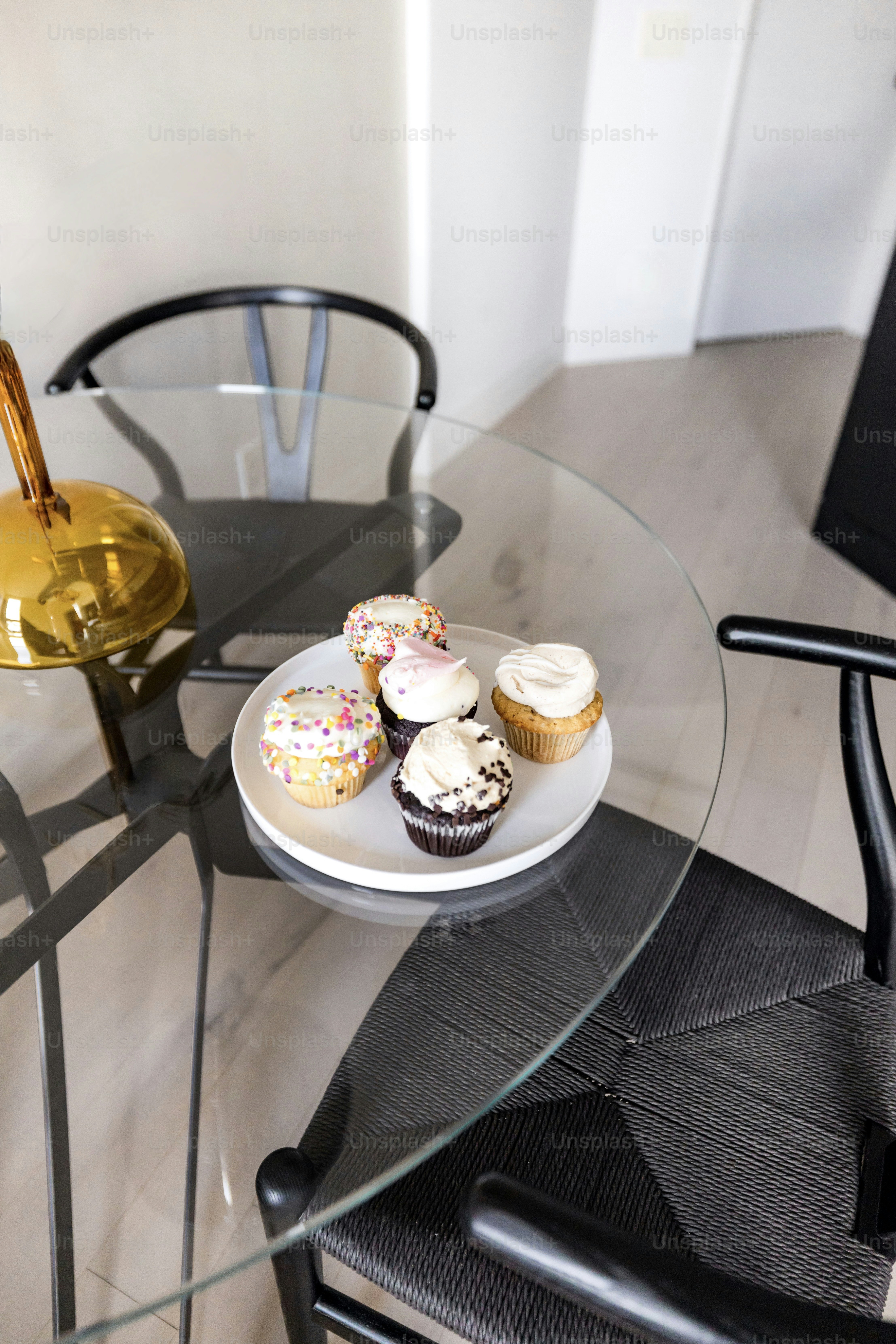 una mesa de vidrio con un plato de cupcakes