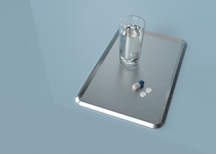 a glass of water and pills on a tray