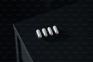 três pílulas brancas sentadas em cima de uma mesa preta