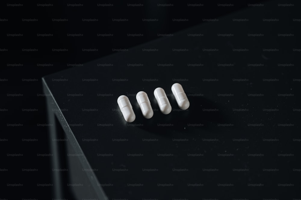 Trois pilules blanches posées sur une table noire