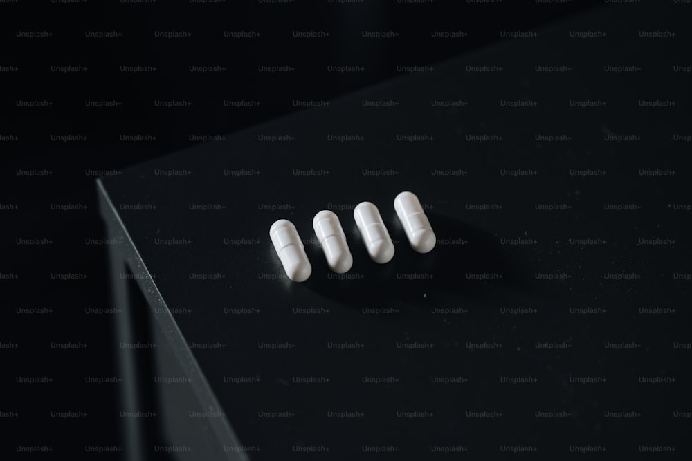 three white pills sitting on top of a black table