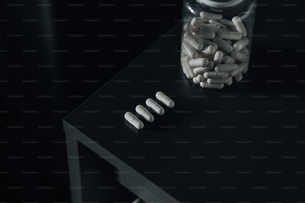 un bocal en verre rempli de pilules blanches assis sur une table
