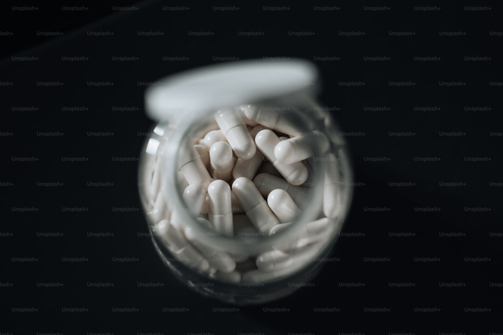 un pot rempli de pilules blanches assis sur une table
