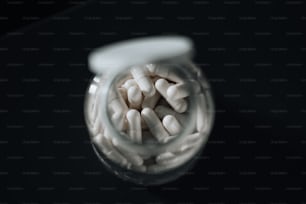 a jar filled with white pills sitting on top of a table