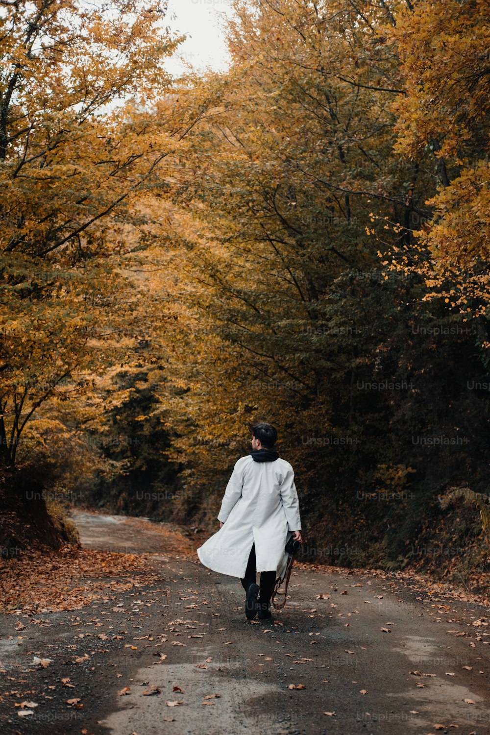 a woman in a white coat walking down a road
