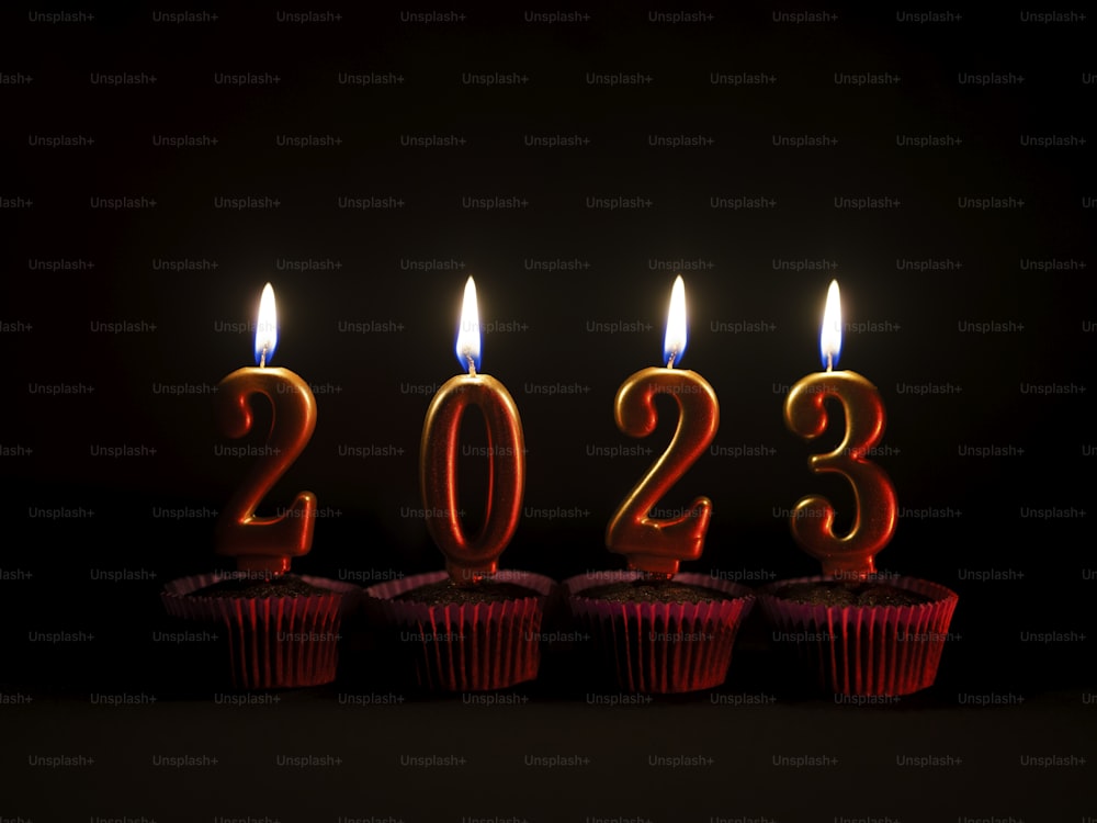 una fila di cupcakes rossi con candele accese a forma di numeri