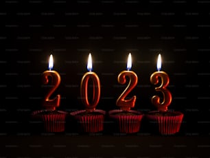Una hilera de cupcakes rojos con velas encendidas en forma de números
