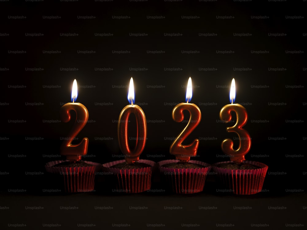 a row of red cupcakes with lit candles in the shape of numbers