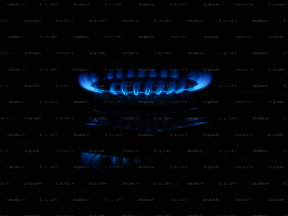 Une cuisinière à gaz avec des flammes bleues dans le noir